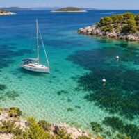 Jacht w chorwackiej zatoce, jasne piaszczyste dno i ciemne łąki Posidonia